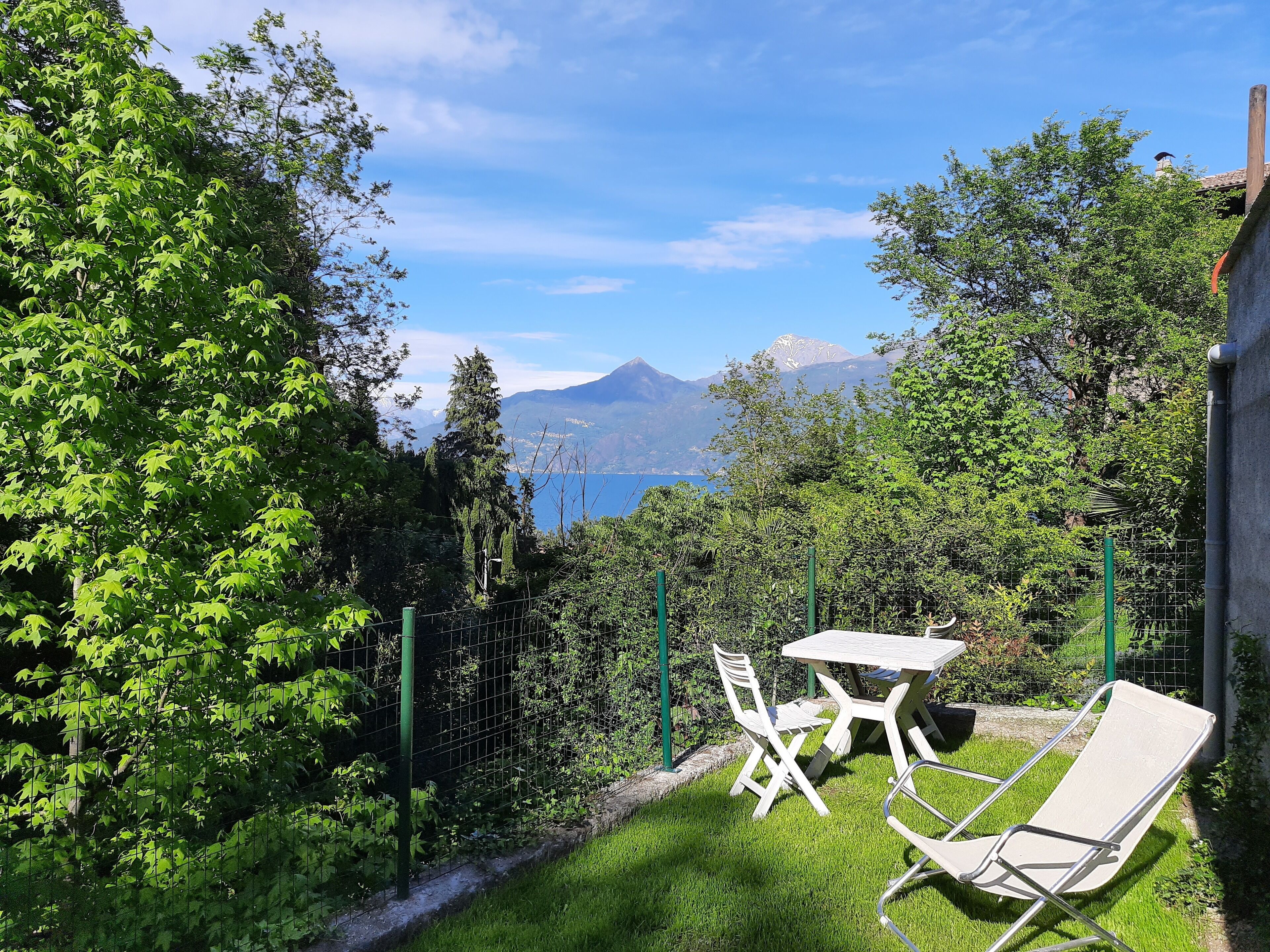 Un jardin avec une table et des chaises, une clôture et une vue sur les montagnes en arrière-plan.