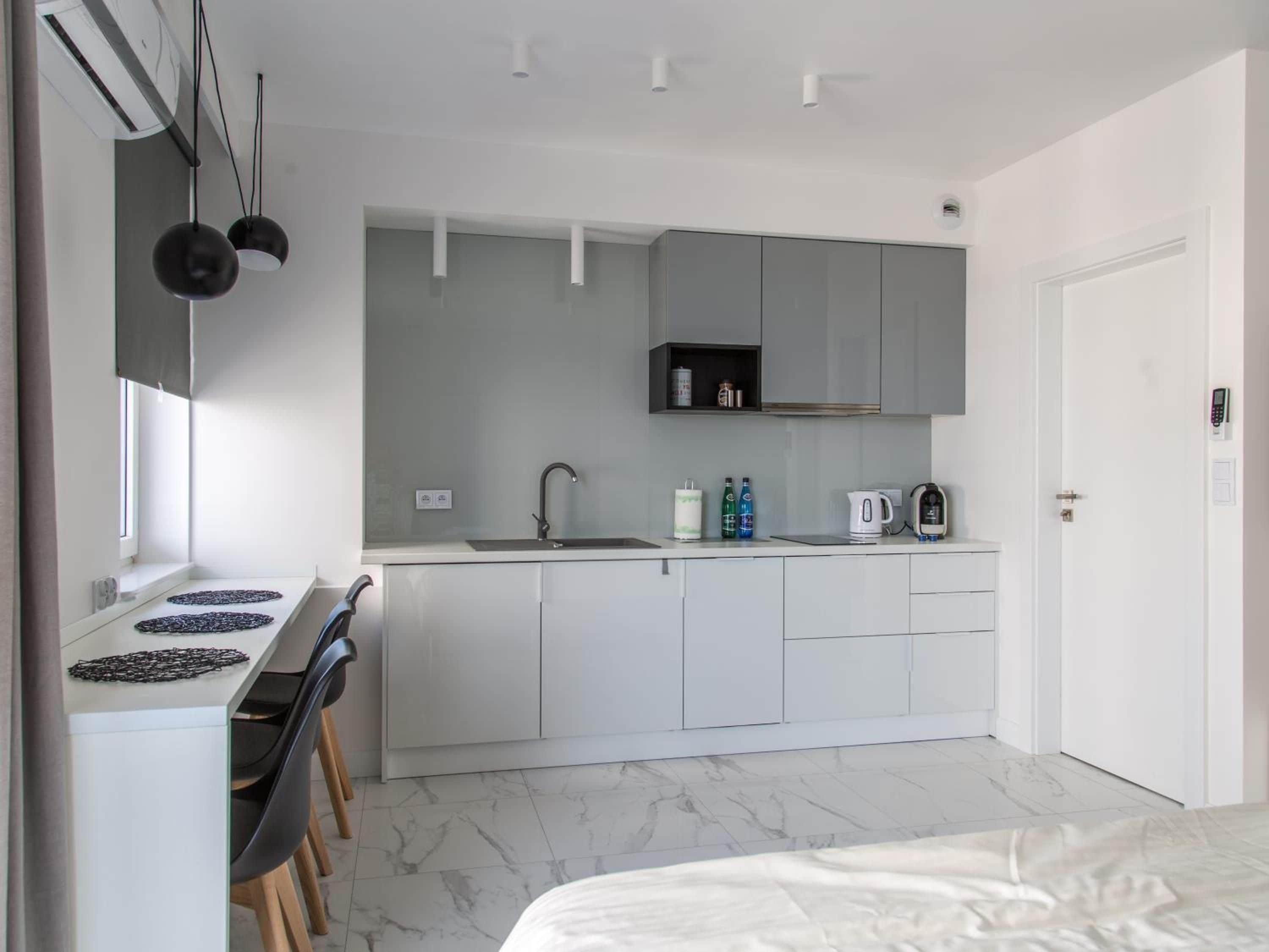 A modern kitchen with a built-in stove, sink, and cabinets. There is a window providing natural light, and a door leading to another room.