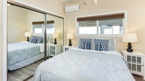 Een slaapkamer met twee bedden, een grote spiegel en een raam.