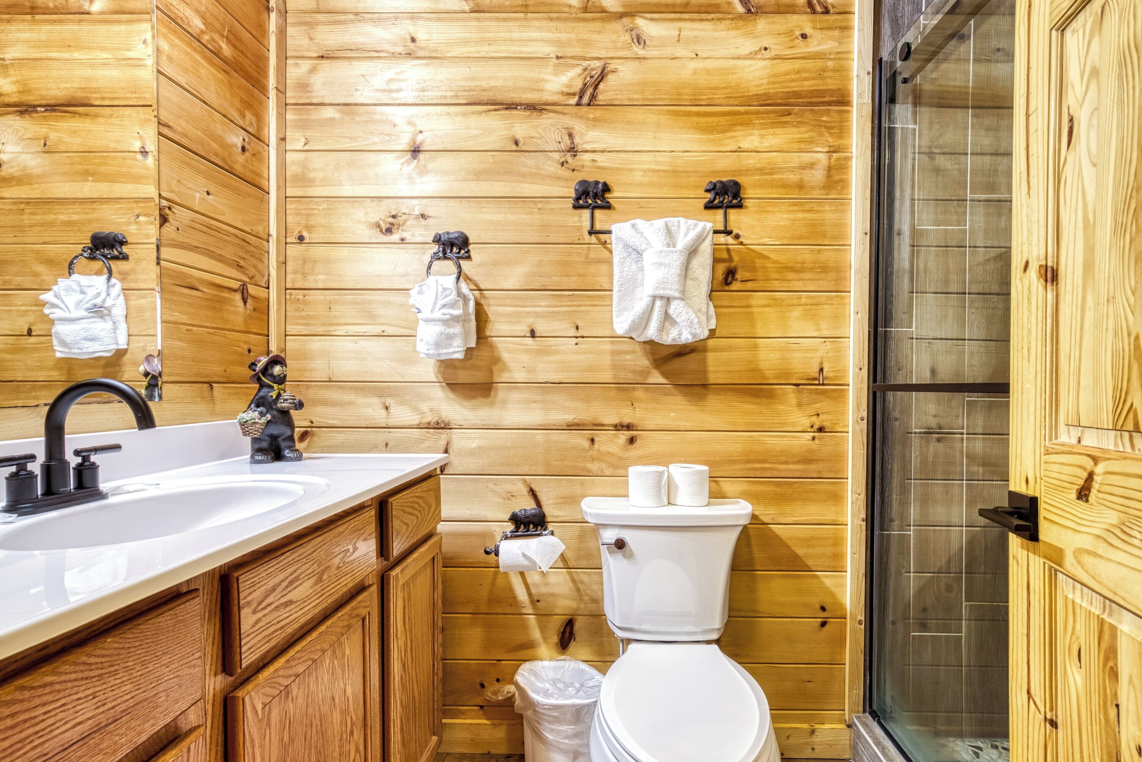 Un baño con paneles de madera, un lavamanos, un inodoro y una ducha.