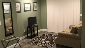 Una sala de estar con un sofá, un televisor, un tapete estampado y cuadros en la pared.