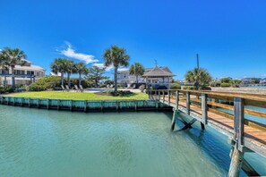 A waterfront property with a wooden dock, a pool, and a gazebo.