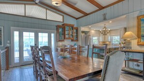 A spacious dining area with a large wooden table, multiple chairs, and a kitchen in the background. - Pop's Place in the private gated community of Inlet Harbour (Garden City Beach)