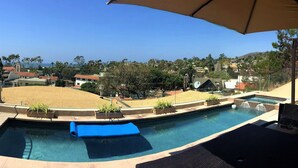 Ein Swimmingpool mit blauer Liegeauflage, Liegestühlen und Sonnenschirm.