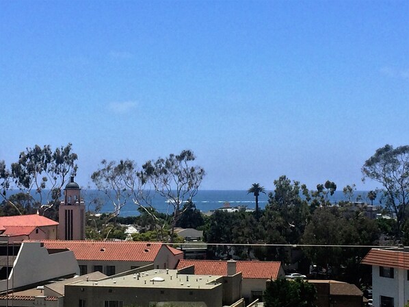 A coastal town with buildings, a bell tower, and a view of the sea.