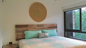A bedroom with a wooden headboard, a bed with a quilted bedspread, a bedside table, and a window with blinds. - Sleeps 5.  Rooftop infinity pool, 2 bed, 2.5 baths, 2nd floor. Walk to cafes. (Tulum)