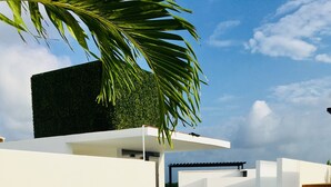 An outdoor seating area with white wicker furniture and blue cushions, a staircase, and a view of the sky. - Sleeps 5.  Rooftop infinity pool, 2 bed, 2.5 baths, 2nd floor. Walk to cafes. (Tulum)