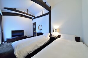 Une chambre d’hôtel moderne avec un grand lit, un bureau, une télévision et un grand miroir rond au mur.