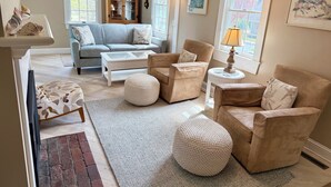 Een woonkamer met een grijze bank, beige fauteuils, een salontafel en een kamerkleed met een patroon.
