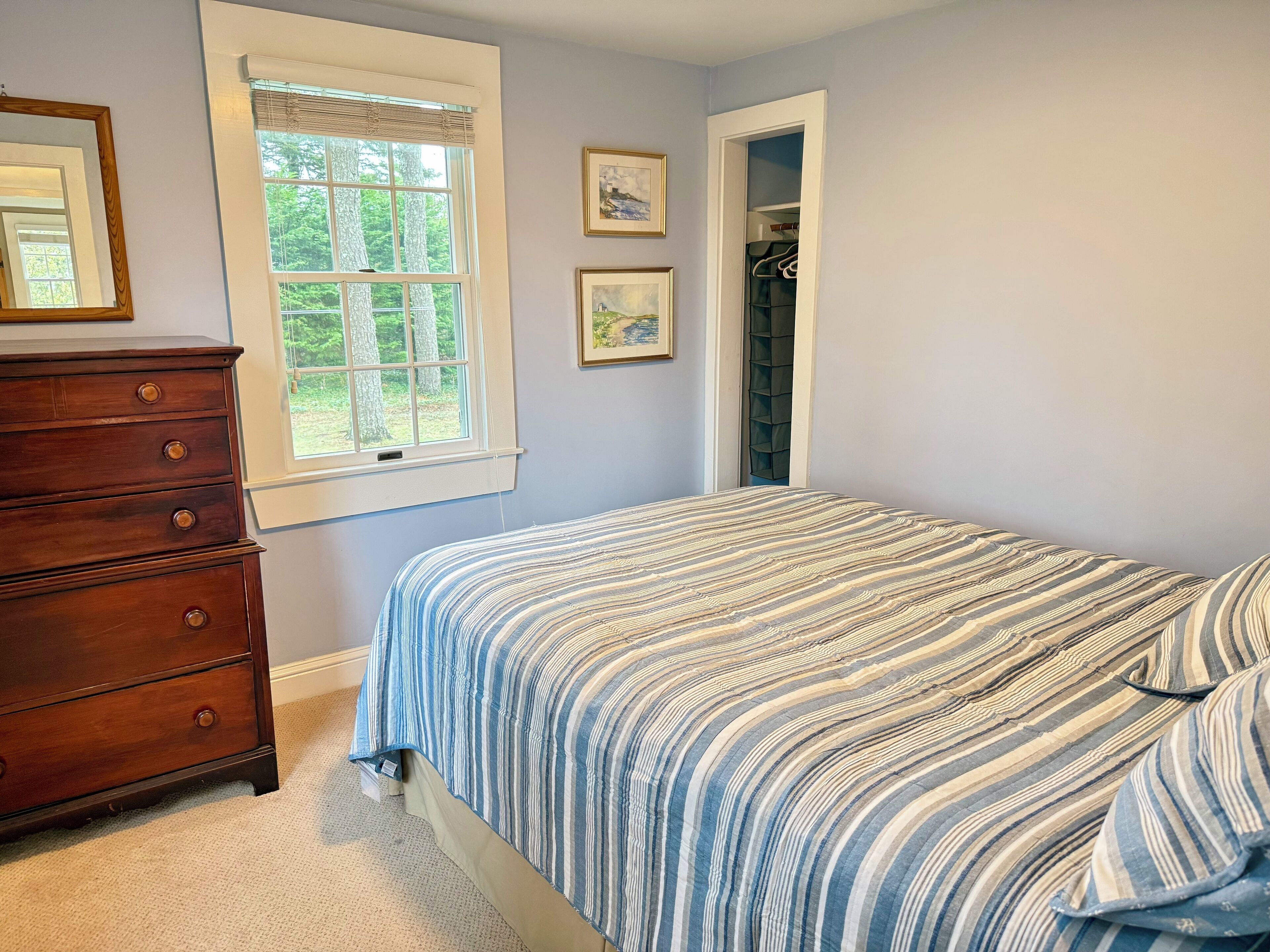 A bedroom with a bed, a dresser, a window, and a closet.