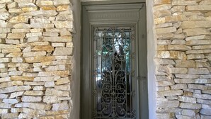 Uma entrada com muro de pedra e portão de metal decorativo.