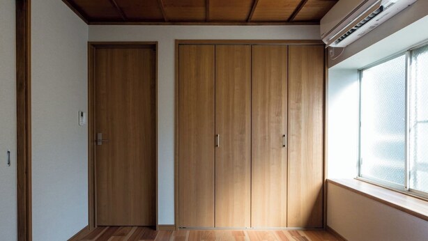 A bedroom with two beds, wooden wardrobes, a window with blinds, and an air conditioning unit. - Japanese Modern Townhouse in Gion with Floor Heat (Kyoto)