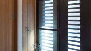 A room with a wooden floor, a sliding door with blinds, and a ceiling light fixture. - Japanese Modern Townhouse in Gion with Floor Heat (Kyoto)