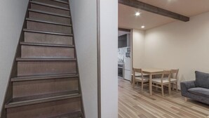 A staircase leading to a room with a dining area, a sofa, and a kitchen in the background. - Japanese Modern Townhouse in Gion with Floor Heat (Kyoto)