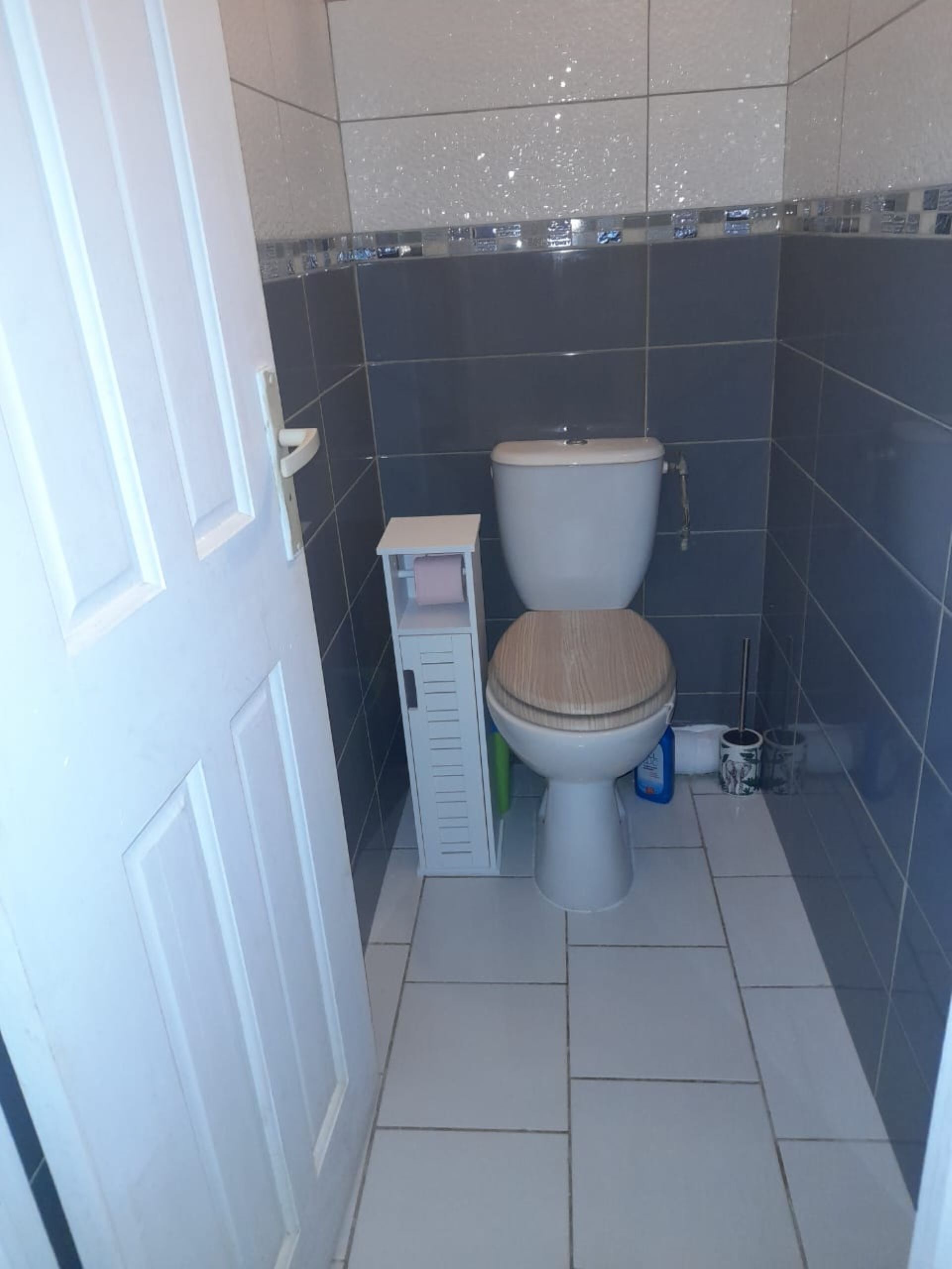 Un baño pequeño con inodoro, un estante y una puerta.