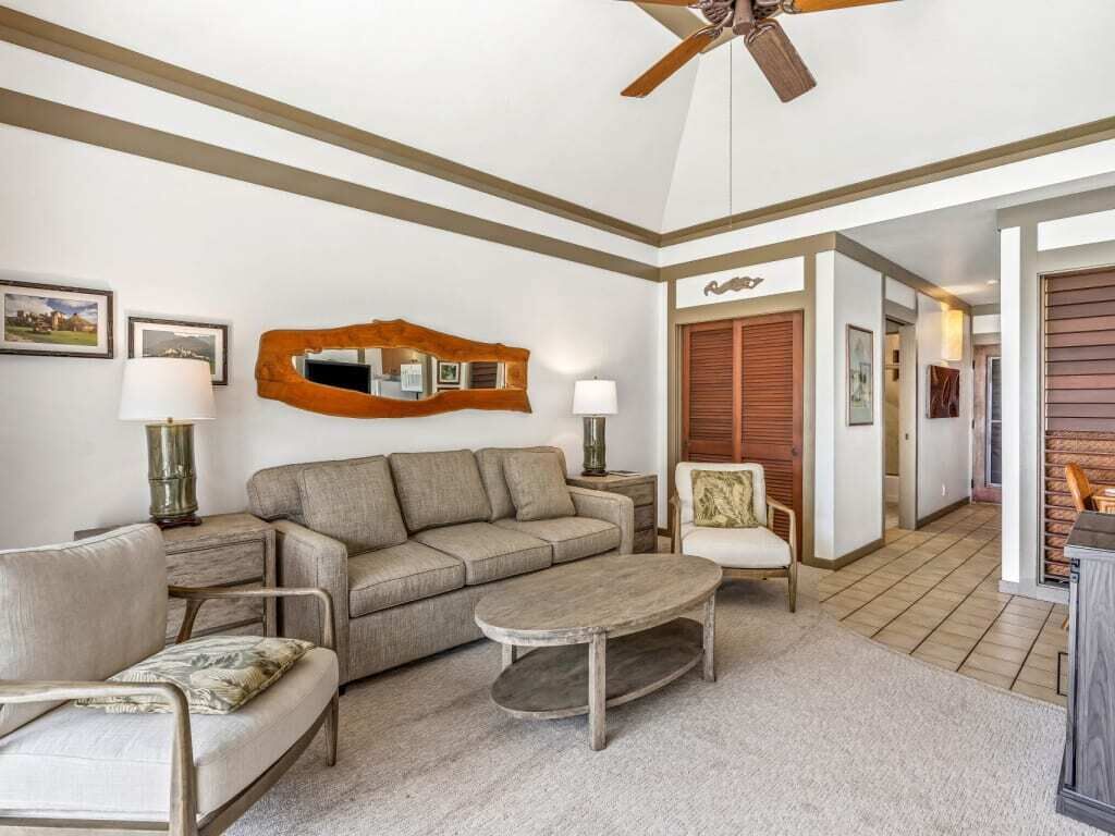 Ein Wohnzimmer mit einer Couch, Sesseln, einem Couchtisch und einem Deckenventilator.
