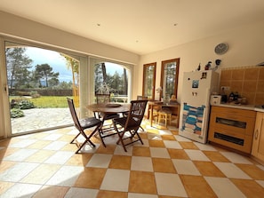 A kitchen with a dining area, large windows, and a view of the outdoors.