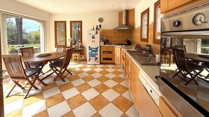 Een moderne keuken met houten kastjes, een groot fornuis en een eetgedeelte met een geruit vloertje.