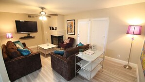 A living room with two sofas, a TV, a fireplace, and a ceiling fan. - Gannet ·- Adorable Condo By Strip- Restaurants,Shopping (Las Vegas)