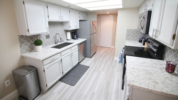 A modern kitchen with white cabinets, a granite countertop, a built-in oven, and a microwave. - Gannet ·- Adorable Condo By Strip- Restaurants,Shopping (Las Vegas)