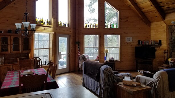 Una cabaña de madera espaciosa con techos altos, ventanas grandes y una sala de estar acogedora con sofá y mesa.