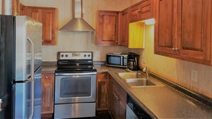 A modern kitchen with stainless steel appliances, wooden cabinets, and a unique fish decoration. - In the HEART of Ocean Drive in North Myrtle Beach (North Myrtle Beach)