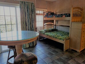 A room with a bunk bed, a wooden cabinet, a glass table, and a chair. - In the HEART of Ocean Drive in North Myrtle Beach (North Myrtle Beach)