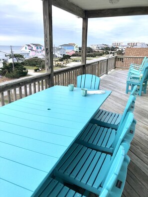 A covered outdoor deck with a turquoise table and matching chairs, overlooking a residential area.