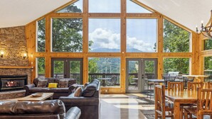 A spacious living area with a stone fireplace, leather sofas, and a large wooden dining table.