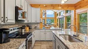 A modern kitchen with granite countertops, white cabinetry, and a large island with a sink.
