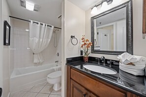Une salle de bain avec une baignoire, des toilettes, un lavabo et un grand miroir.