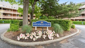 Un panneau indiquant l’accès à « Arrowhead Court », entouré d’un espace paysager agrémenté de diverses plantes et d’un arbre.