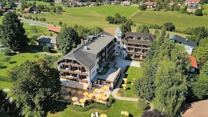 Un grand hôtel avec de nombreux étages, des espaces extérieurs aménagés pour s’asseoir et un jardin bien entretenu.
