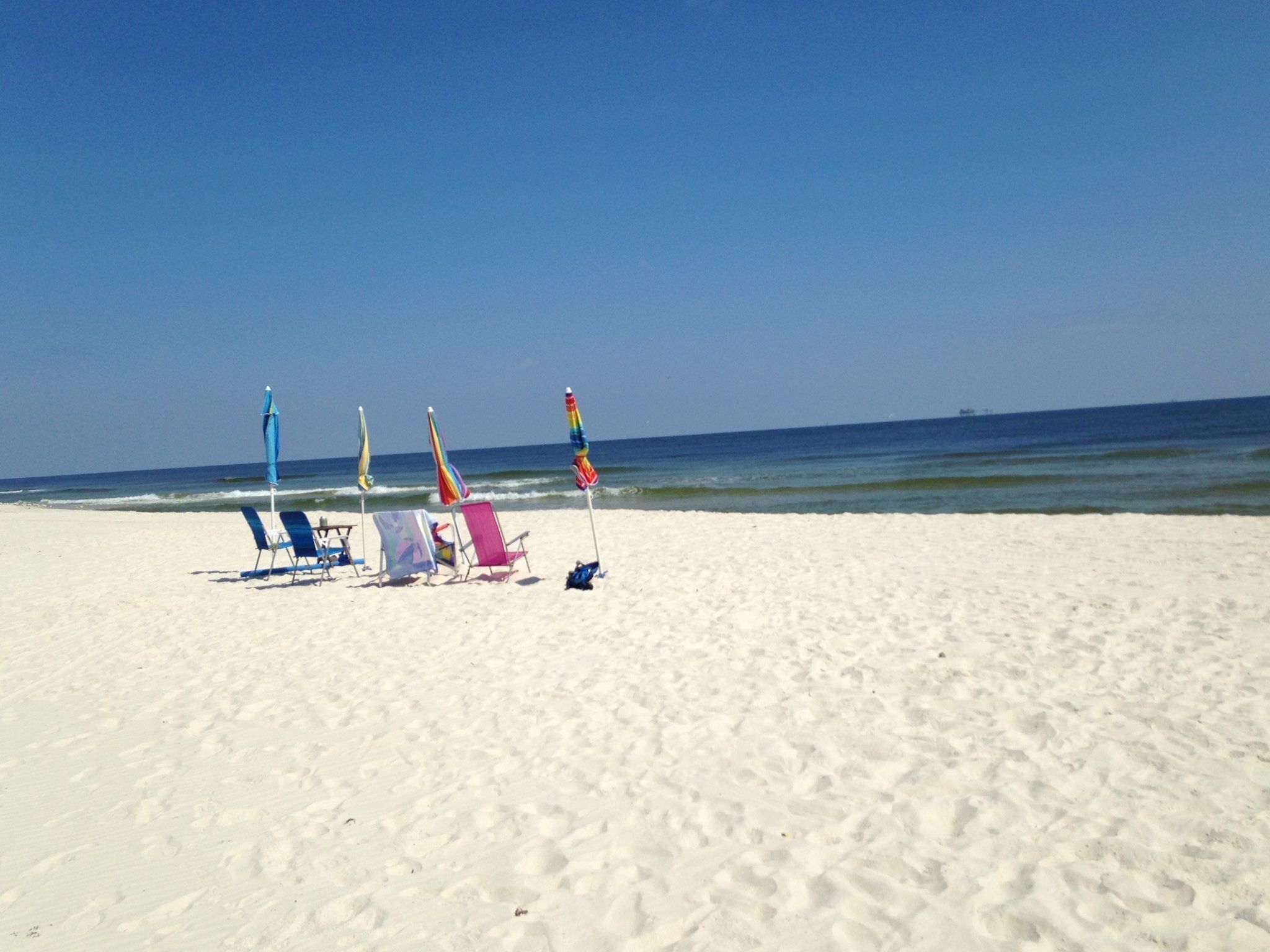A beach with several beach chairs and umbrellas.