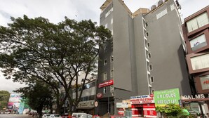 A multi-story building with commercial signage, including a liquor store and a parking shop. - Stylotel By Jagadish (Bengaluru)