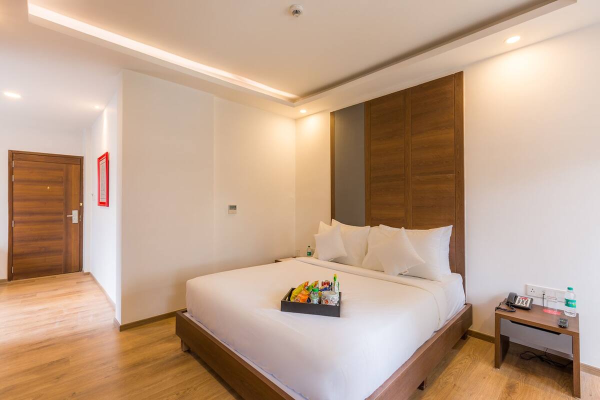 Una habitación de hotel con una cama grande, una mesita de noche y un armario de madera.