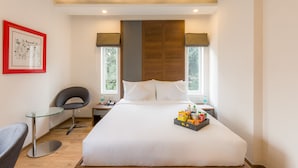 A hotel room with a large bed, a glass table, a modern chair, and a framed picture on the wall. - Stylotel By Jagadish (Bengaluru)