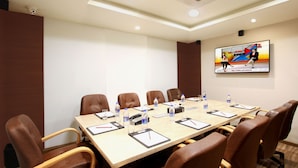 A conference room with a long table, brown leather chairs, water bottles, notepads, and a clock. - Stylotel By Jagadish (Bengaluru)