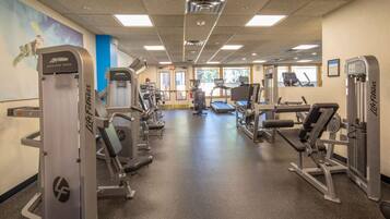 A gym with various exercise machines, a treadmill, and a wall with a poster.