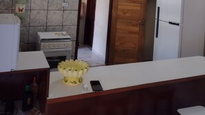 Une cuisine avec un réfrigérateur blanc, une porte en bois, un pare-feu en carrelage et un luminaire au plafond.