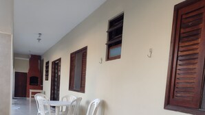 Un couloir au sol carrelé, un coin repas avec une table et des chaises, et des volets en bois aux murs.