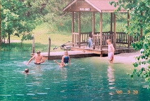 Relax by the pool at our serene outdoor oasis, featuring a wooden dock and a beach shack pavilion.