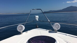 The bow of a boat with a clear view of the water and distant land.