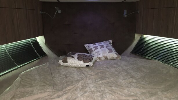 A room with a bed, two pillows, a ceiling light, and a window with blinds.