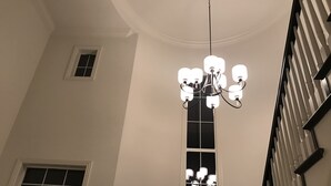 Un lustre composé de plusieurs luminaires est suspendu au plafond d’une pièce aux murs blancs et dotée d’une grande fenêtre.