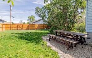 Ein Garten mit einem Holztisch und einem Holzzaun.