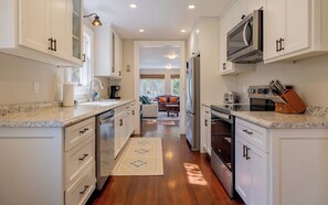 A modern kitchen with white cabinets, stainless steel appliances, and a granite countertop.