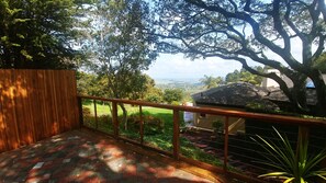 Enjoy the serene view of lush green landscapes and distant hills from this outdoor deck.