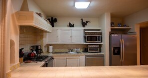 A kitchen with white cabinets, a microwave, a refrigerator, and a stove. - Ocean Front/Heated Pool, 6 Adults+ 2 kids under 12 (Puerto Vallarta)