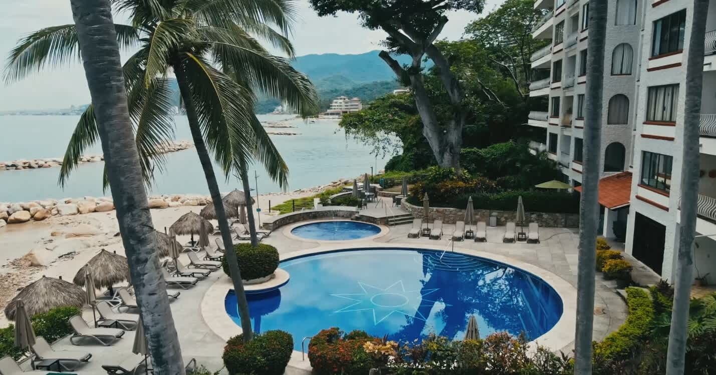 Een resort met een zwembad, ligbedden en uitzicht op zee.